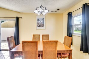 Un comedor con una mesa y sillas de madera, una lámpara de techo y una ventana con cortinas.