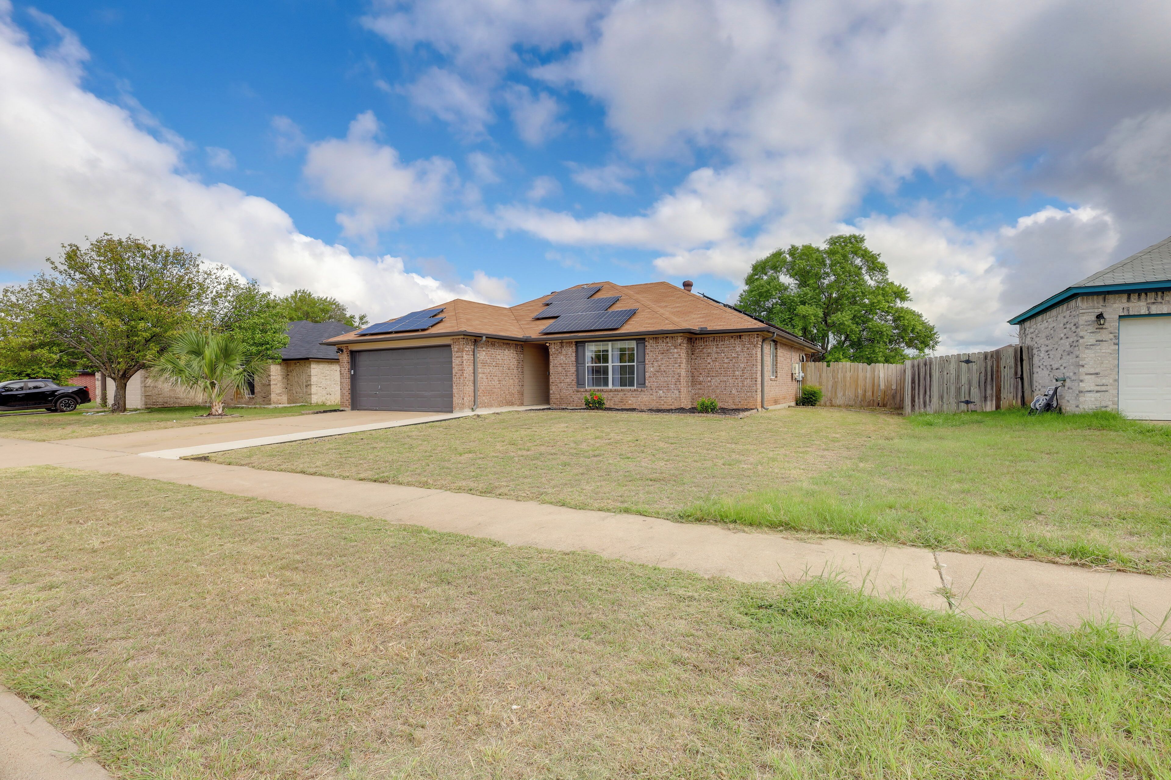 A residential house with a brick exterior, a garage, and a front yard with a sidewalk.