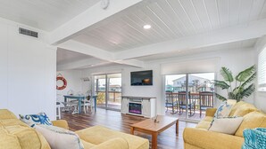 A spacious living room with yellow sofas, a wooden coffee table, and a fireplace. - Enjoy the View, Walk to Beach! Galveston Hideaway (Galveston)