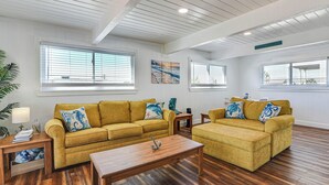 A spacious living room with two mustard-colored sofas, a wooden coffee table, and a painting on the wall. - Enjoy the View, Walk to Beach! Galveston Hideaway (Galveston)