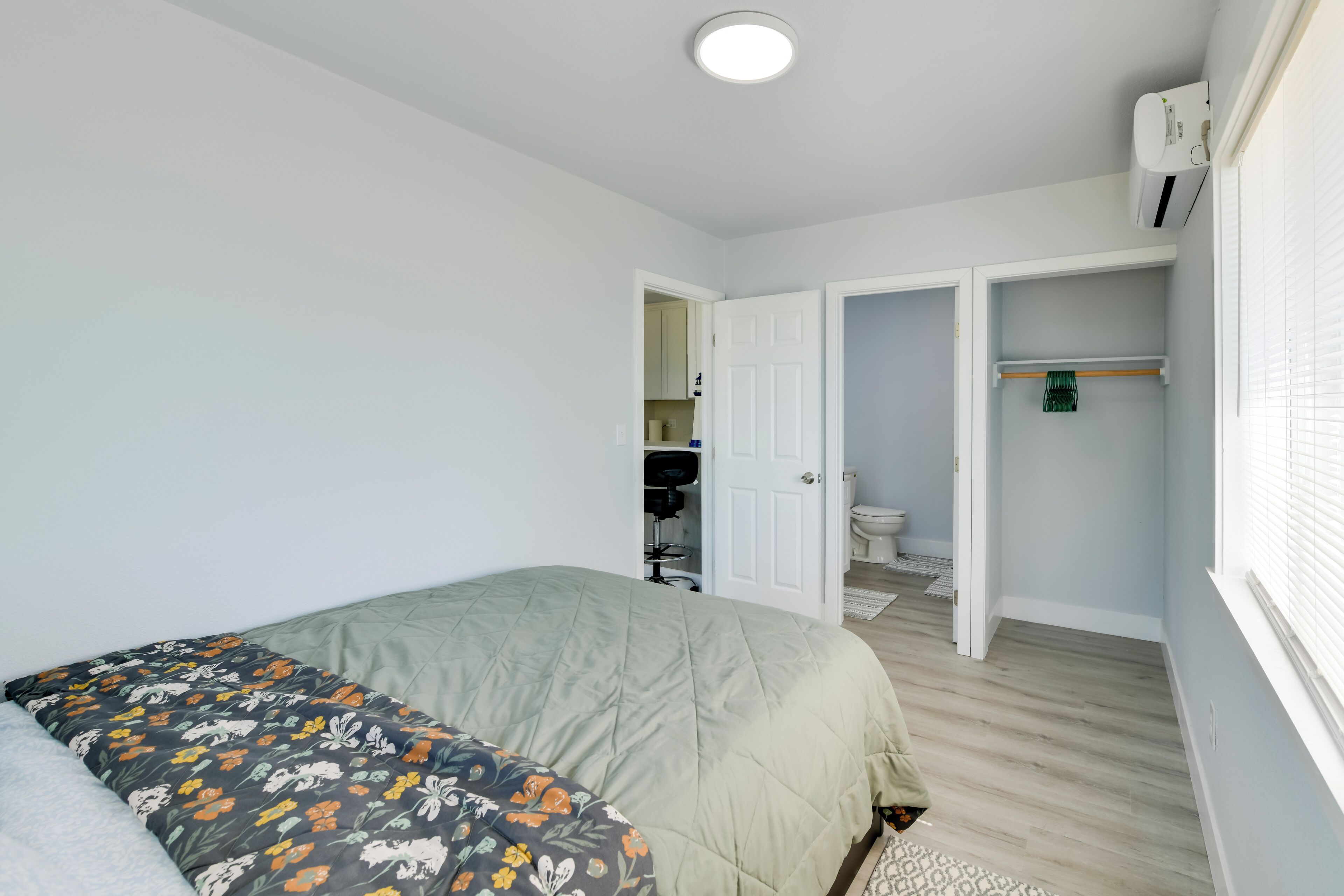 A bedroom with a bed, a closet, and a bathroom visible through an open door.