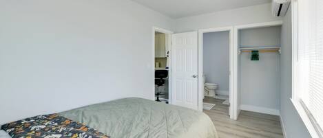 A bedroom with a bed, a closet, and a bathroom visible through an open door.
