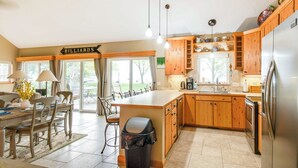 A spacious kitchen with wooden cabinets, a stainless steel refrigerator, and a dining area with a table and chairs.