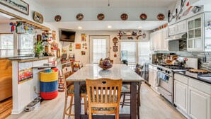 Una cocina amplia con una isla grande, armarios blancos y diversos objetos decorativos.