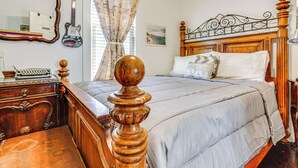 Un dormitorio con una cama de madera, un aparador, un espejo y una guitarra.
