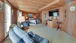 A cozy room with a bed, a sofa, a TV, and a small table with a lamp. - Waterfront Jonesville Studio on Black River Lake! (Jonesville)