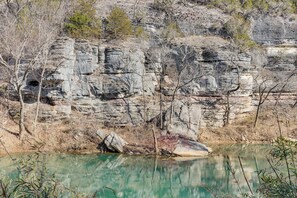 Un paisaje natural con un risco rocoso y una masa de agua tranquila.