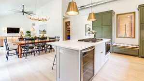 Una cucina moderna con isola centrale, illuminazione a sospensione e forno a incasso.