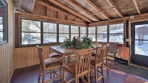 A wooden interior with a large table and chairs, large windows, and a door leading outside. - Snowmobile, Ice Fish & Explore! Lang Lake Cabin (Danbury)