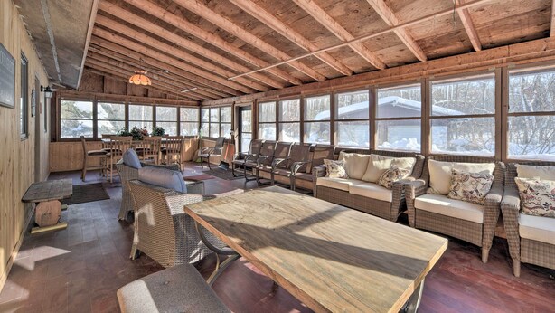 A spacious indoor area with wooden beams, large windows, and comfortable seating arrangements. - Snowmobile, Ice Fish & Explore! Lang Lake Cabin (Danbury)