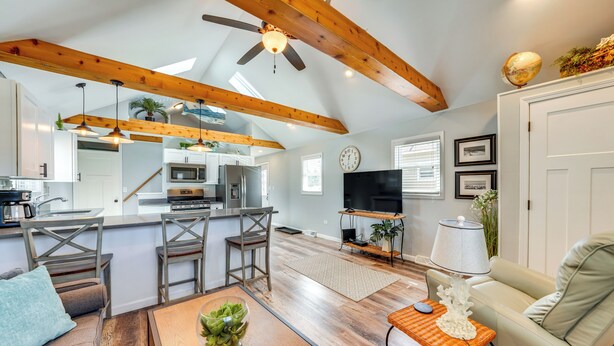 Un'ampia zona giorno con soffitto in legno, una cucina con elettrodomestici moderni e un'accogliente area salotto con tavolino.