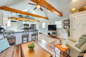 A spacious living area with a wooden ceiling, a kitchen with modern appliances, and a comfortable seating area with a coffee table.
