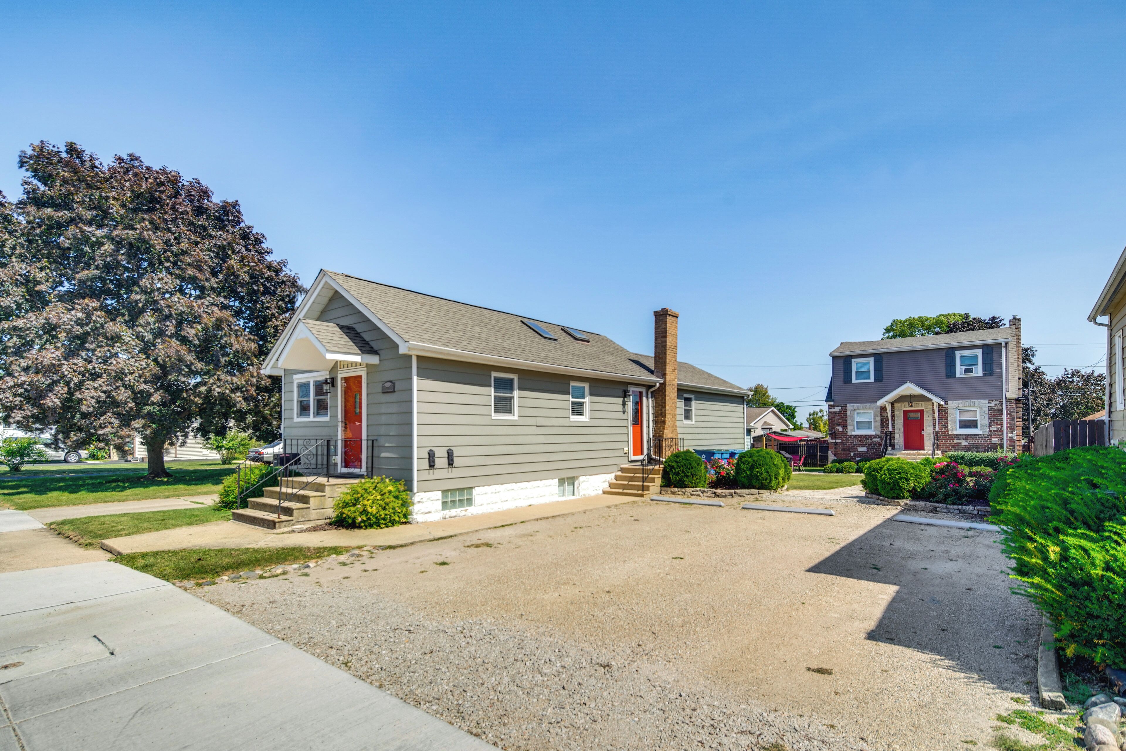 A residential house with a front porch, a chimney, and a driveway.