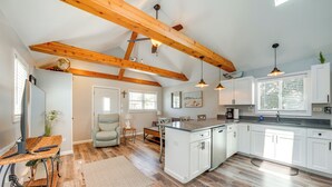 Un'ampia cucina con mobili bianchi, soffitto in legno e zona pranzo con tavolo e sedie.