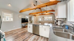 Una cucina moderna con travi in legno, lavastoviglie, lavello e un'ampia finestra.