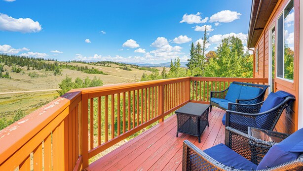 Eine Holzterrasse mit Gartenmöbeln und Blick auf eine grüne Landschaft.