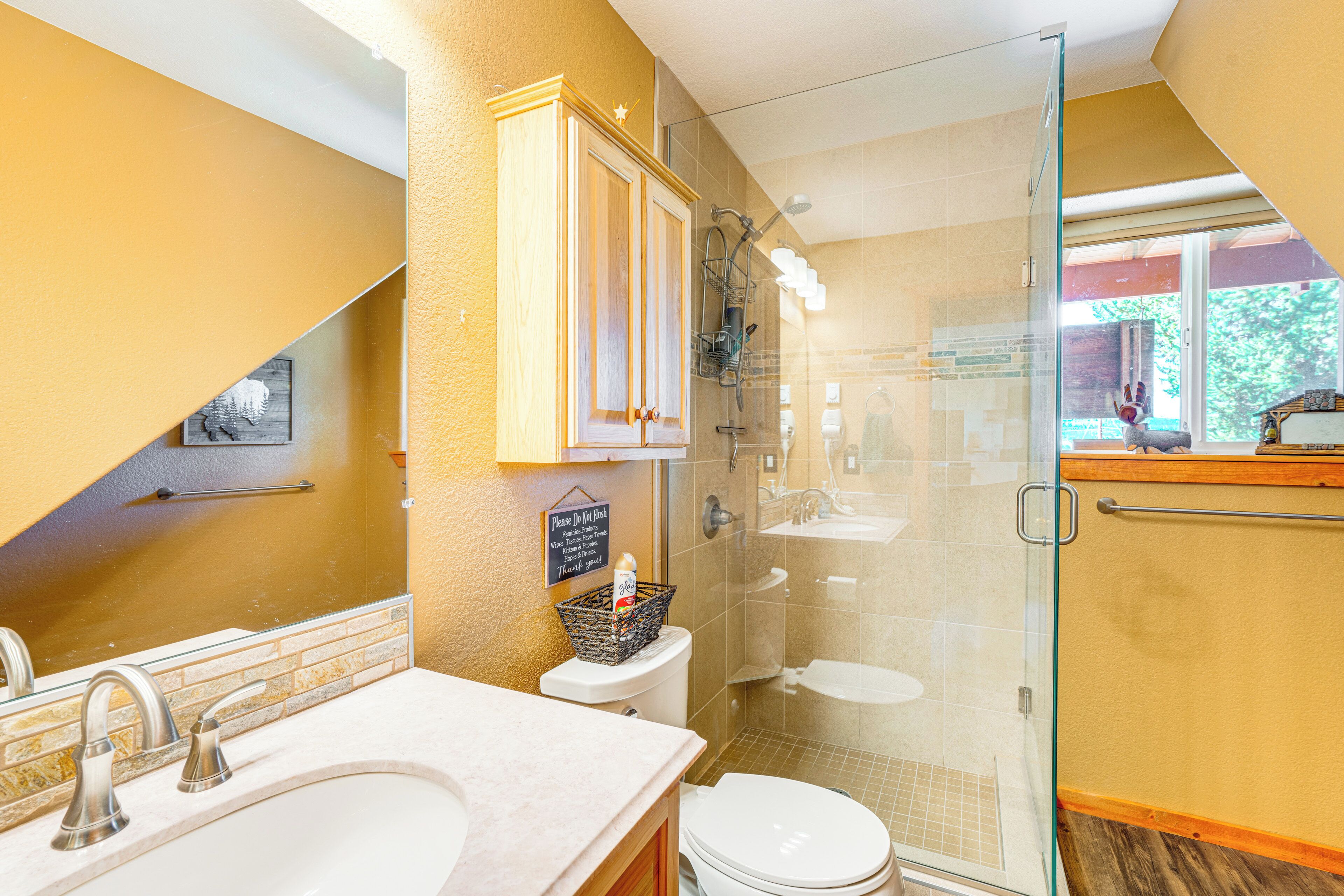 A modern bathroom with a glass shower enclosure, a white toilet, and a sink with a towel rack.