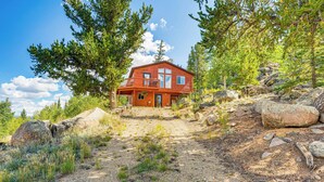 Eine rustikale Holzhütte mit Balkon, umgeben von Bäumen und felsigem Gelände.