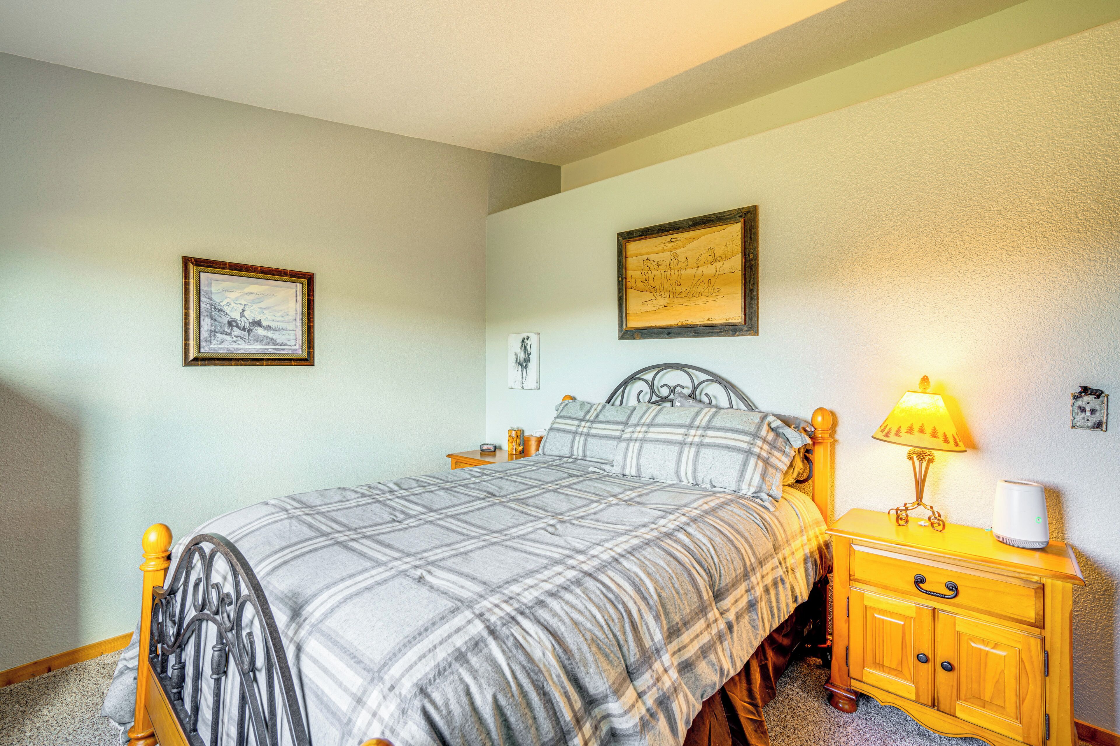 A bedroom with a bed, a nightstand, a lamp, and two framed pictures on the wall.