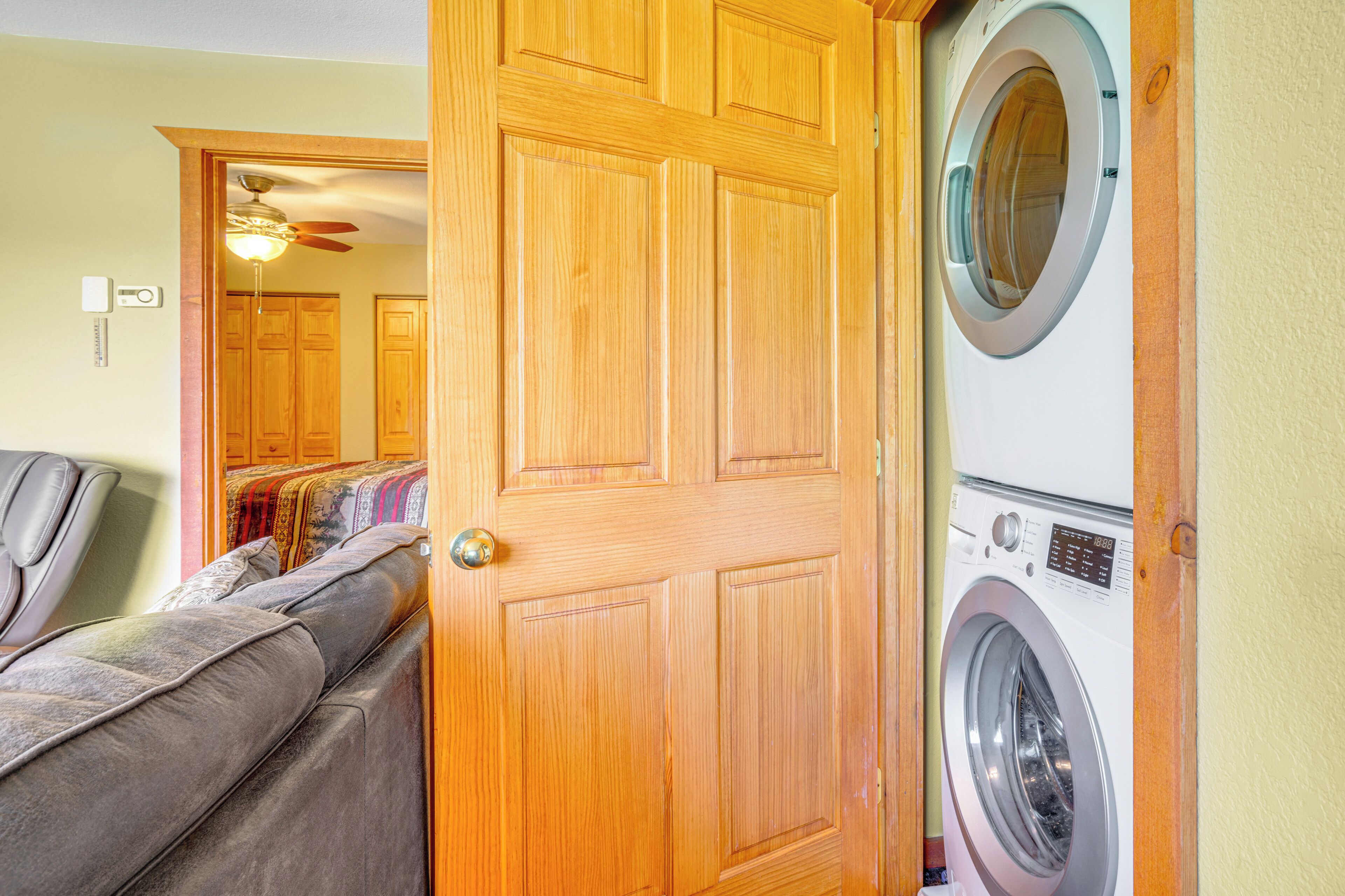 A laundry room with a washing machine and dryer, a wooden door, and a sofa with cushions.
