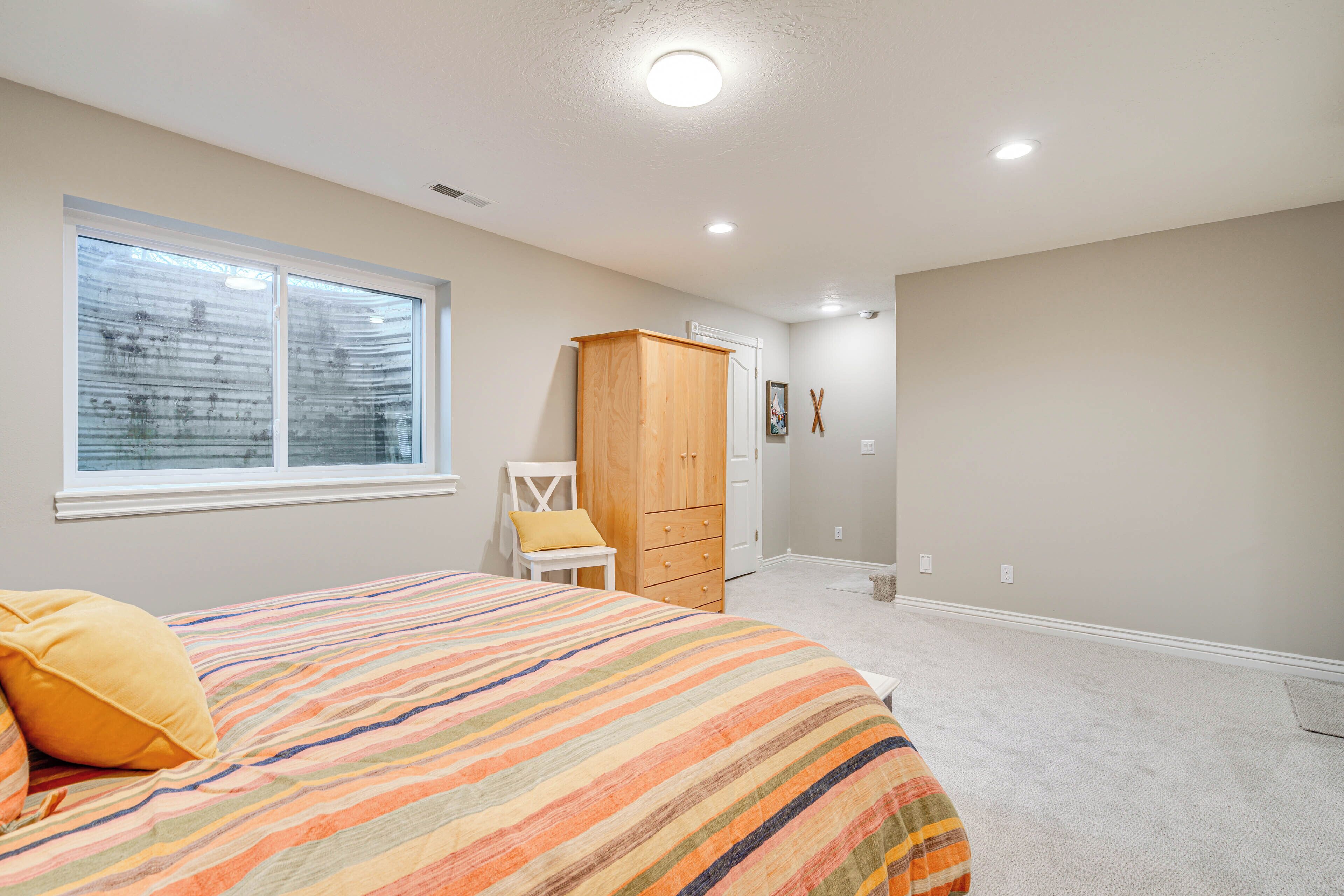Un dormitorio con cama, armario, silla, ventana y puerta.