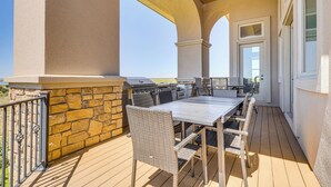 An outdoor patio with a stone wall, a wooden deck, and a covered seating area with a table and chairs. - Game Room & Deck: Group Getaway in New Mexico! (Tucumcari)