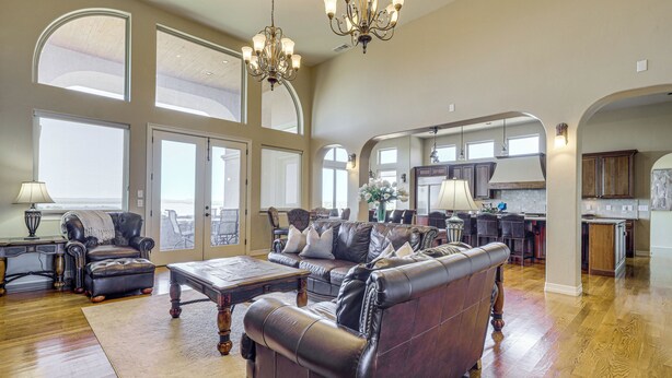 A spacious living room with a leather sofa, a coffee table, and a chandelier. - Game Room & Deck: Group Getaway in New Mexico! (Tucumcari)