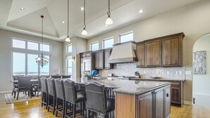 A spacious kitchen with a large island, dark wooden cabinets, and a dining area with bar stools. - Game Room & Deck: Group Getaway in New Mexico! (Tucumcari)