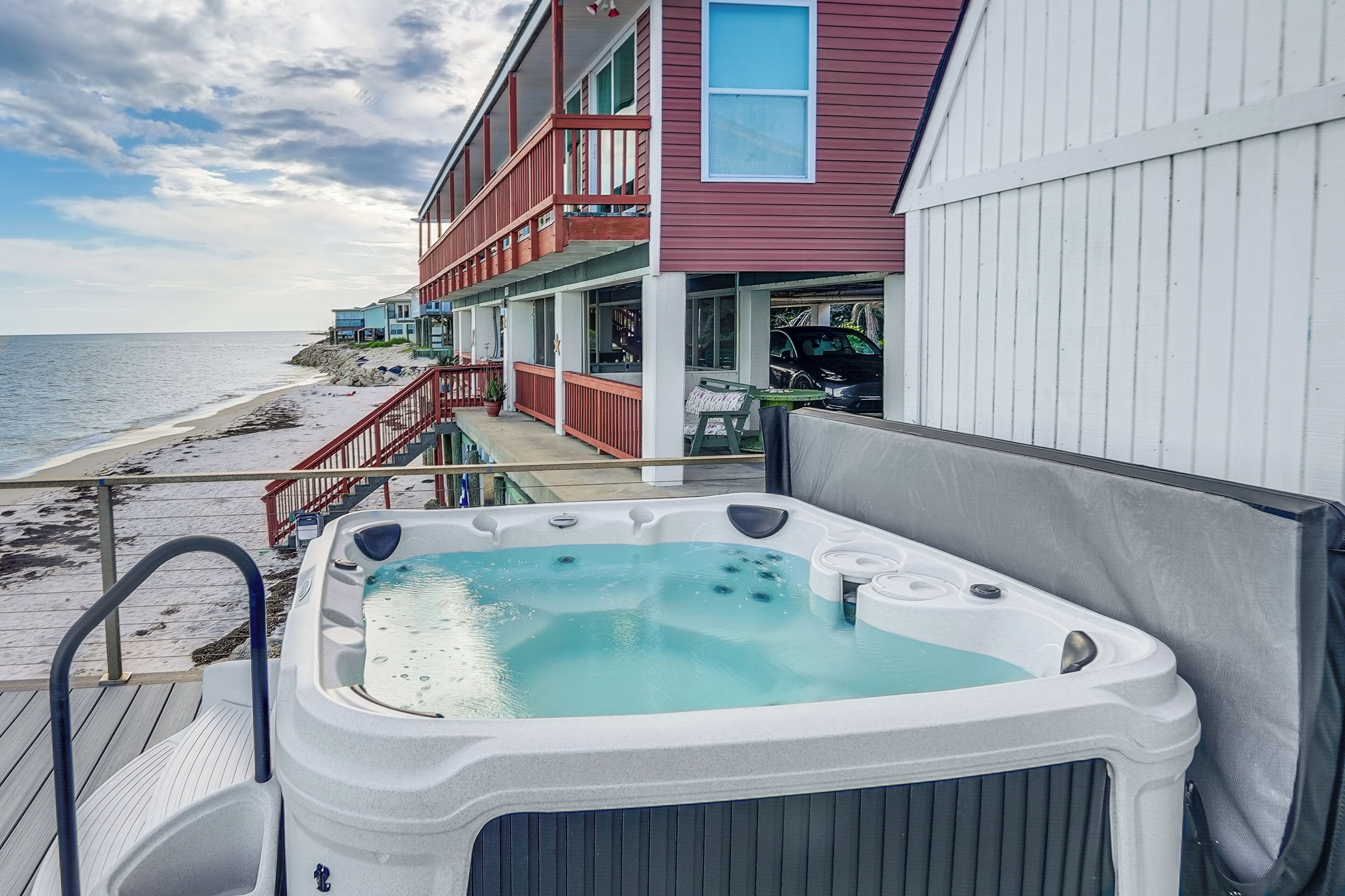Un jacuzzi en una terraza con vista a la playa y un edificio con balcones.