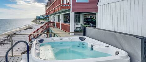 Un jacuzzi en una terraza con vista a la playa y un edificio con balcones.