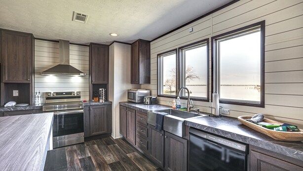 A modern kitchen with dark wood cabinets, stainless steel appliances, and a large window providing natural light. - Sunset Cove Lakefront Rental w/ Private Dock! (Onalaska)