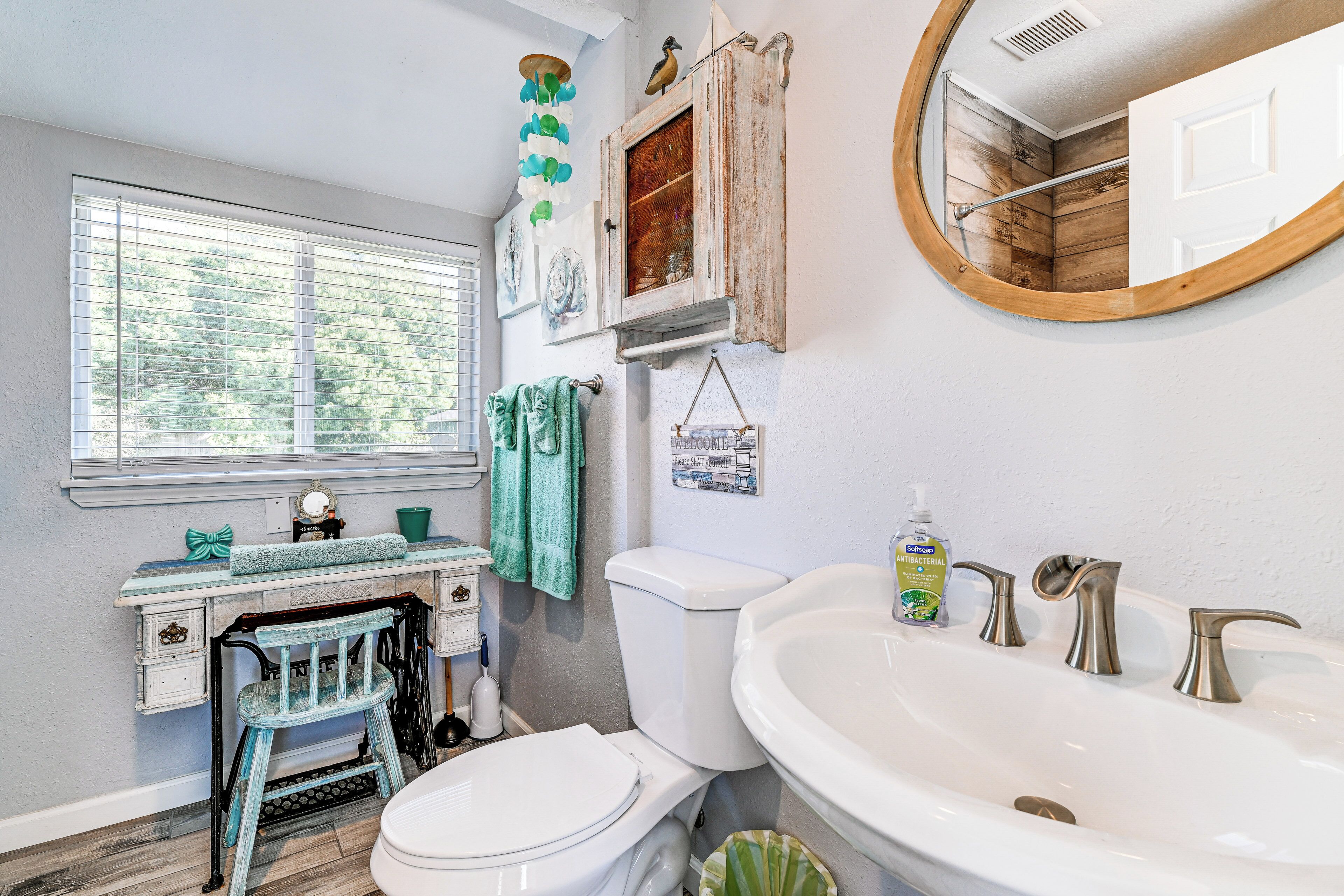 A bathroom with a toilet, sink, and window.