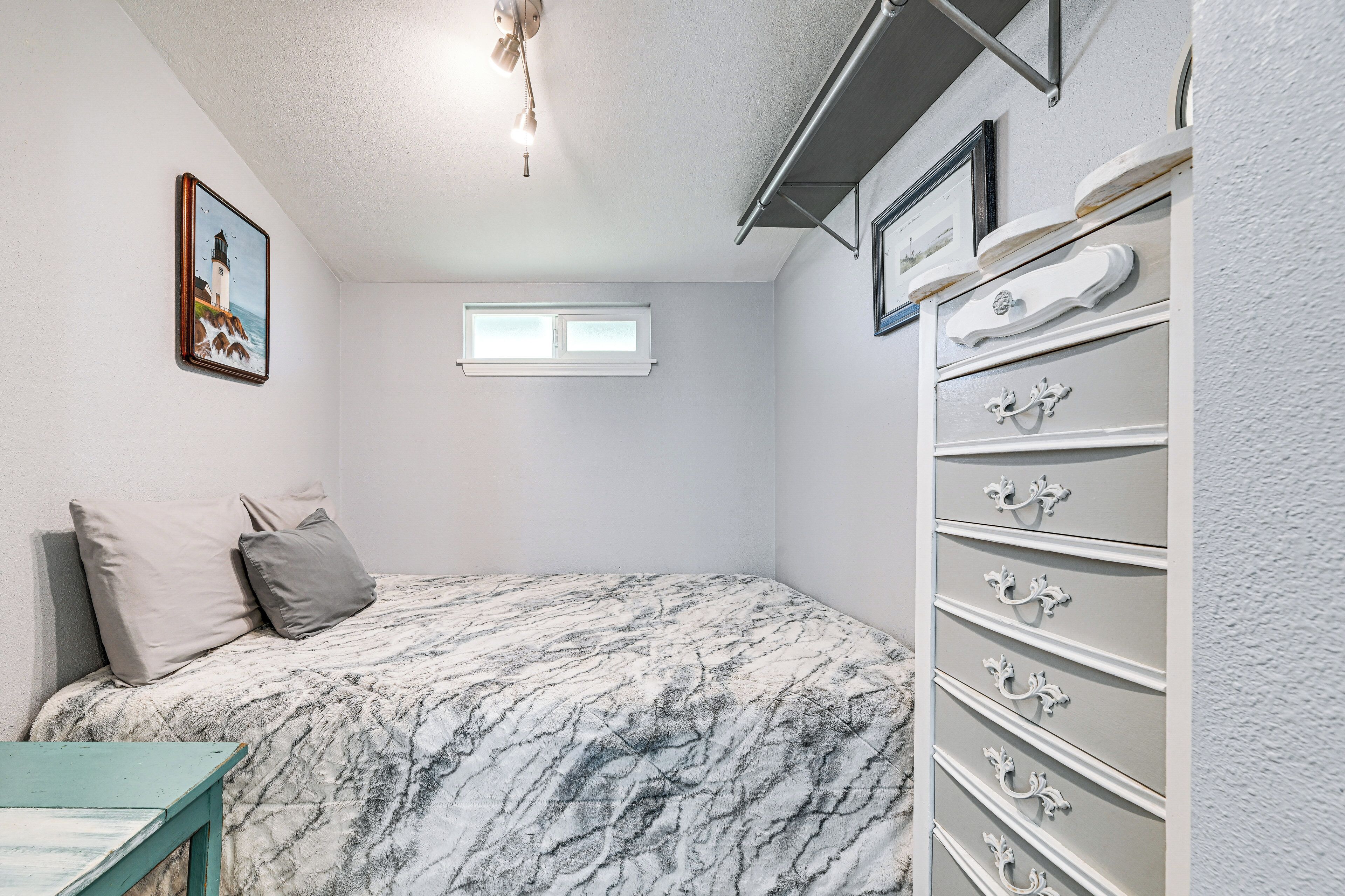 Quarto com cama, penteadeira, janela e um quadro na parede.