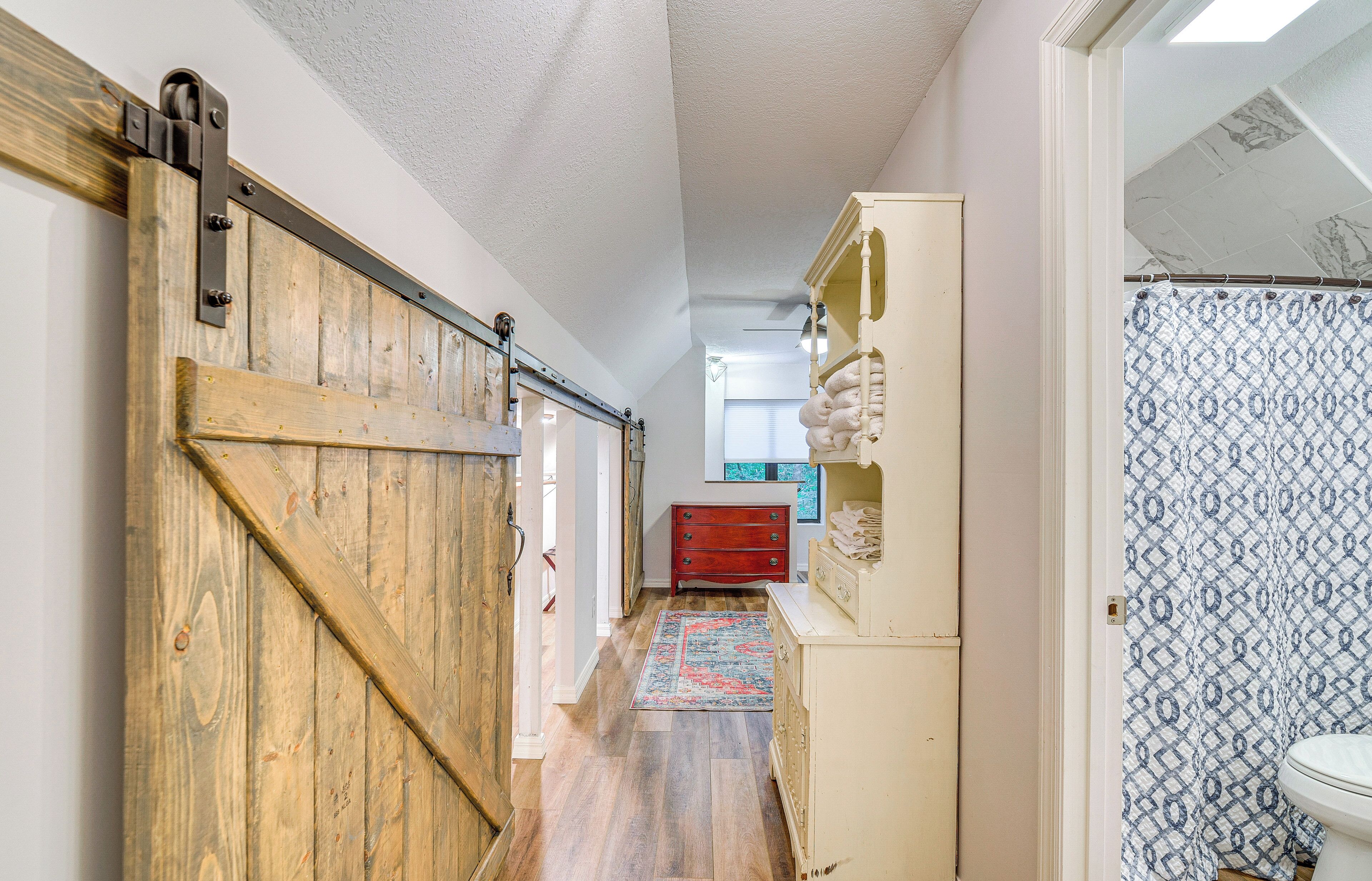 A hallway with a wooden sliding door, a red dresser, and patterned curtains.