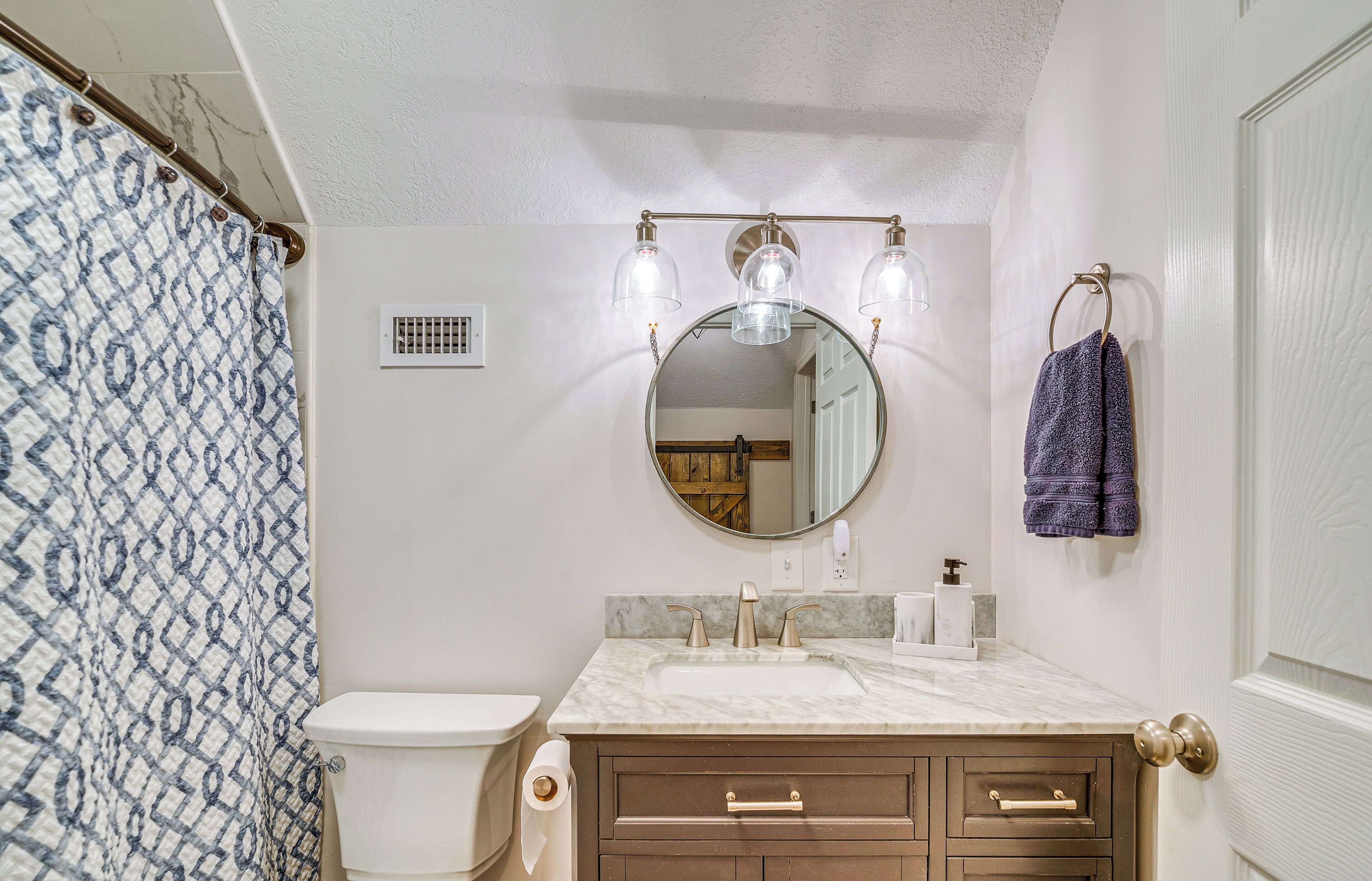 Un baño con inodoro, lavamanos, tocador y espejo con luces.