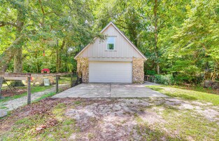 A single-story building with a garage, surrounded by trees and a fenced area.