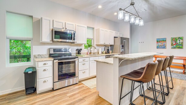 A modern kitchen with white cabinets, stainless steel appliances, and a bar area with stools. - 3 Mi to Silver Springs State Park: Cozy Getaway! (Silver Springs)