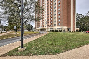 A multi-story building with a one-way street sign, a grassy area, and a sidewalk.