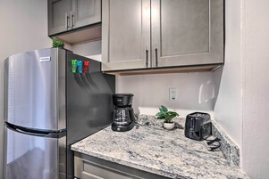 A kitchen with a stainless steel refrigerator, a coffee maker, a toaster, and a potted plant on the counter.