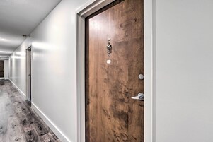 Un pasillo con una puerta de madera, un picaporte metálico y una cerradura.