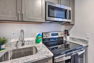 A kitchen with stainless steel appliances, a granite countertop, a sink, and a bag of Bounty paper towels.