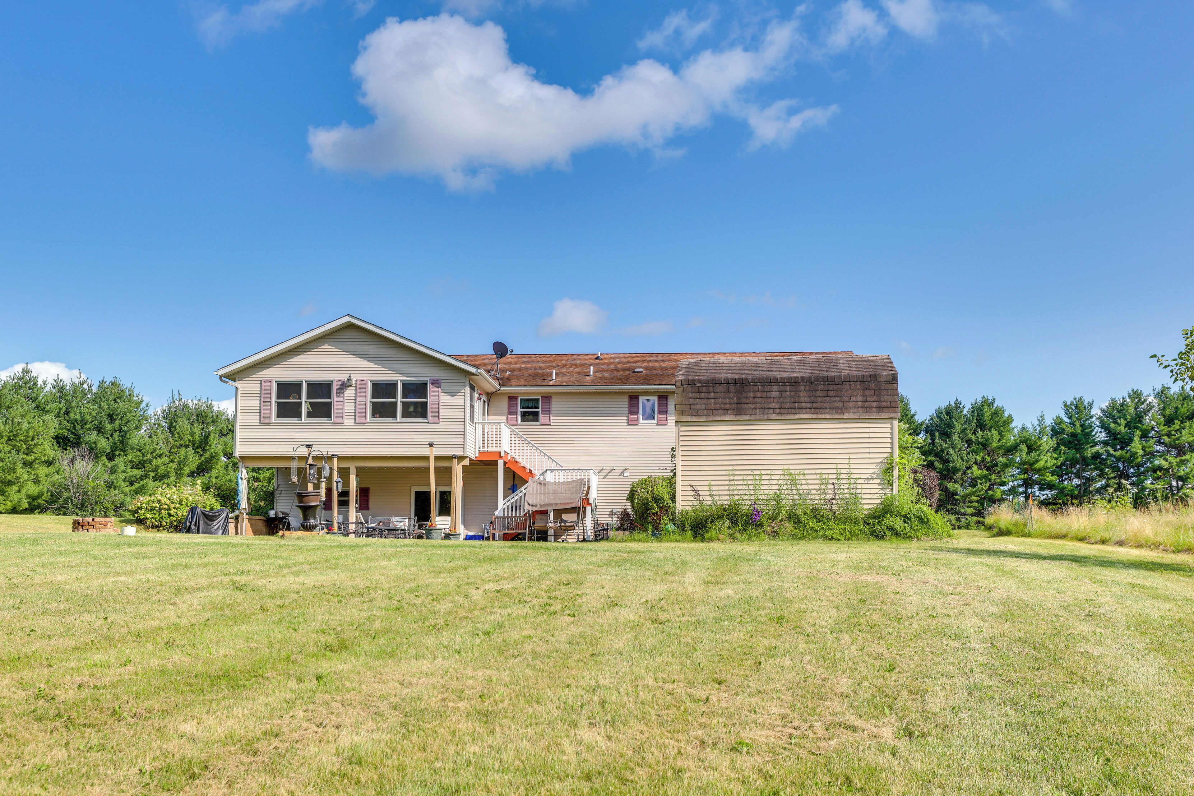 A two-story house with a front porch, a covered patio, and a large lawn.