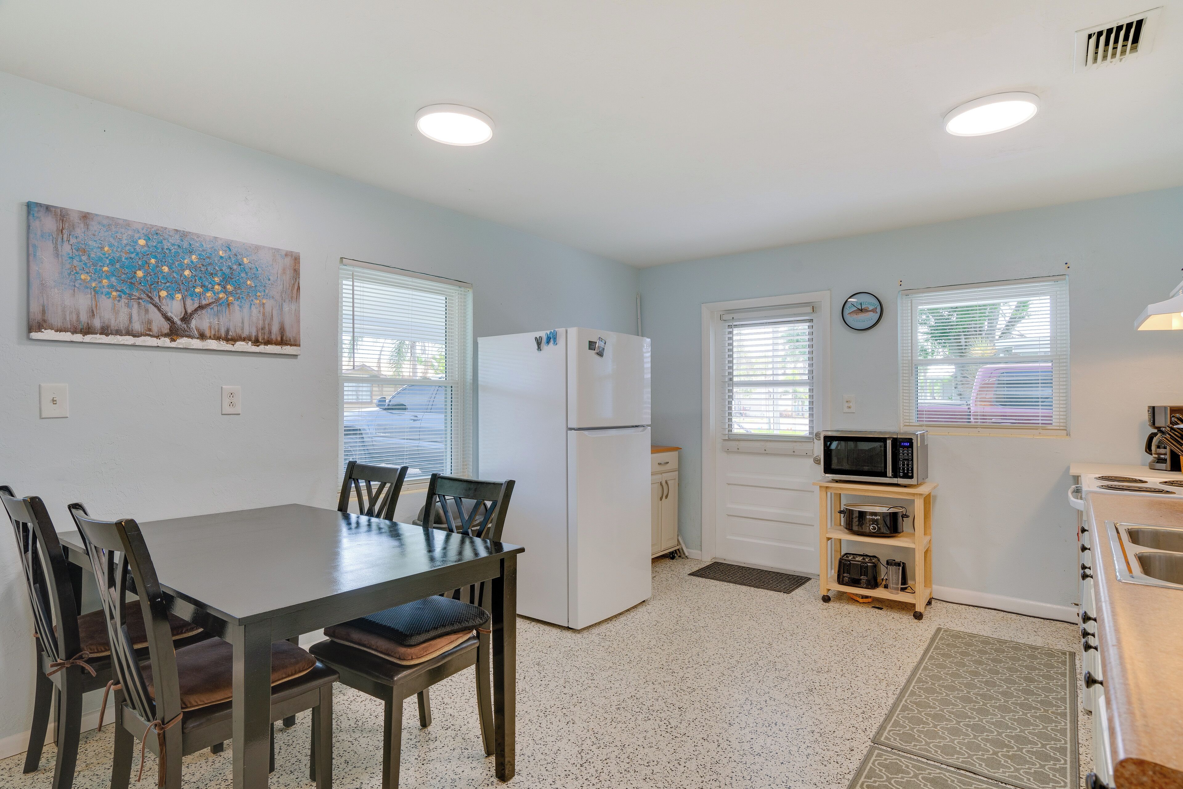 A compact kitchen with a dining table, chairs, a refrigerator, microwave, and a small pantry.