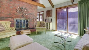 Una sala de estar con chimenea de ladrillo, un sofá, un sillón y una mesa de centro de vidrio.