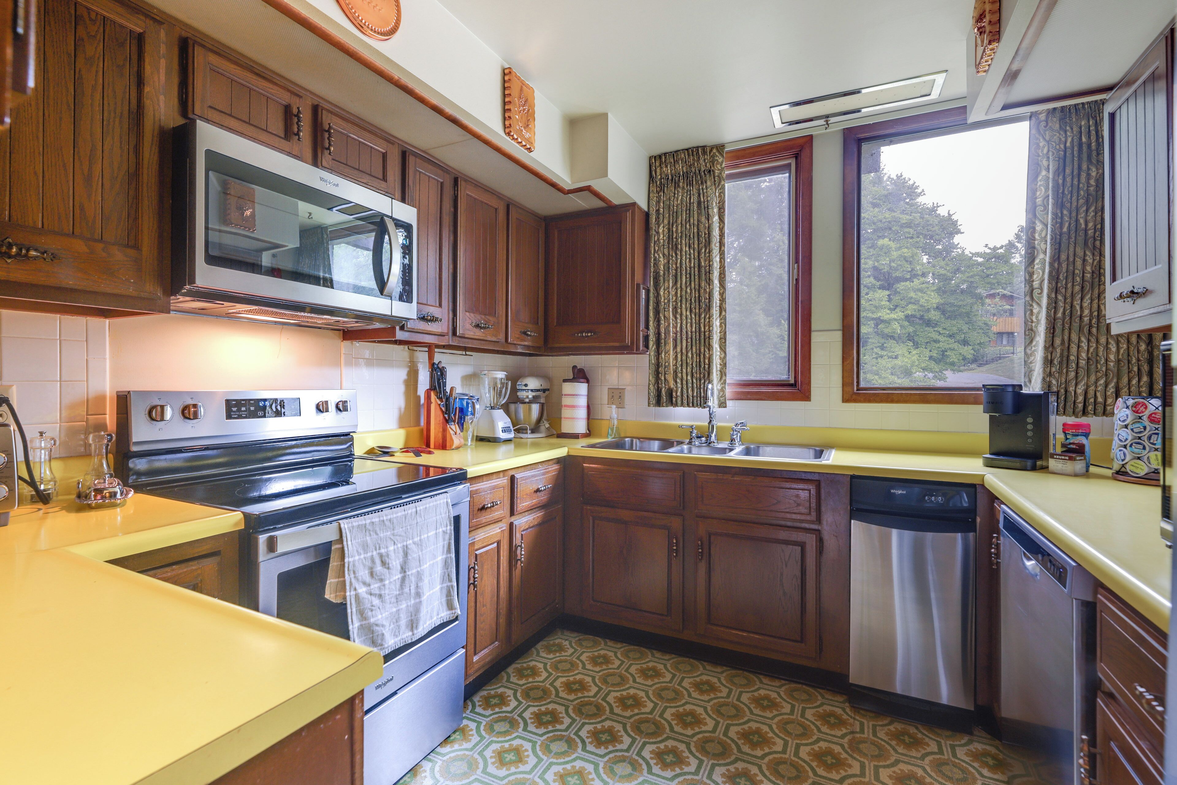 A kitchen with wooden cabinets, a microwave, stove, and dishwasher.