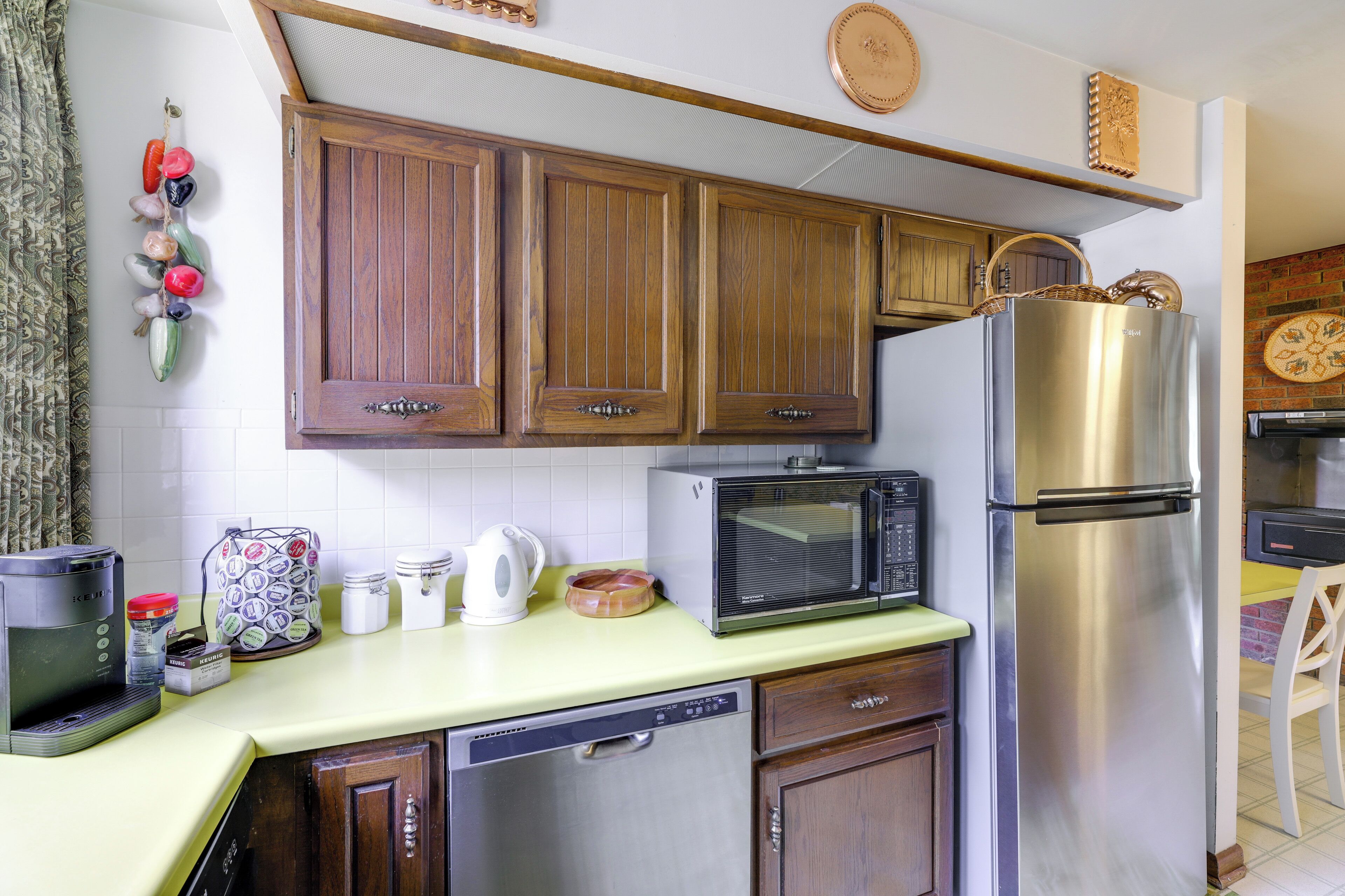 A kitchen with wooden cabinets, a stainless steel refrigerator, a microwave, and a coffee maker.