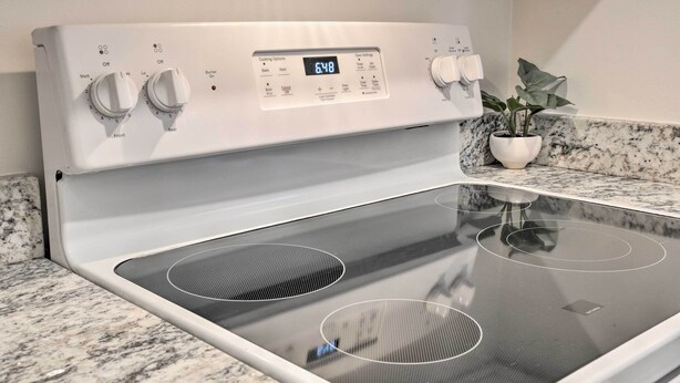 A modern kitchen with a built-in stovetop and oven, featuring control knobs and a digital display. - Ideally Located Studio w/ Off-street Parking! (Gadsden)