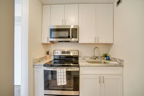A compact kitchen with white cabinets, a stainless steel stove, a microwave, and a sink. - Bright Gadsden Apartment ~ 10 Mi to Dive Land Park (Gadsden)