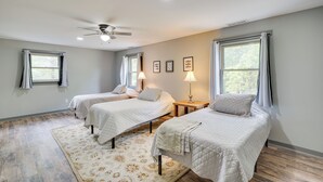 Une chambre avec deux lits, un ventilateur de plafond et une grande fenêtre avec des rideaux.