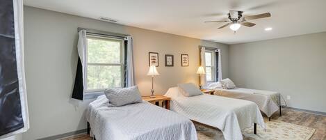 Dormitorio con dos camas, ventilador de techo y ventana con cortinas.